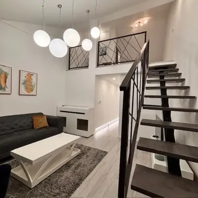 a living room with a couch and a staircase at Urban Maisonette in Banja Luka