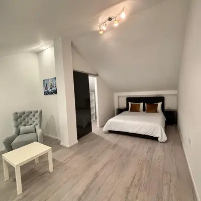 a bedroom with a bed and a chair at Urban Maisonette in Banja Luka