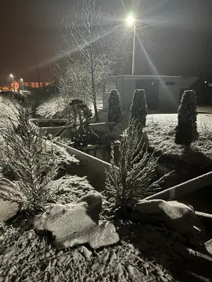 a snow covered garden with trees and a street light at Apartman Čolić - Kupres in Kupres