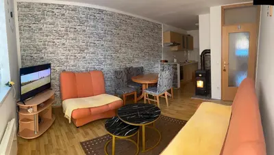 a living room with orange furniture and a brick wall at Apartman Svalina in Kupres