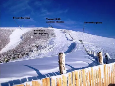 a snow covered hill with a fence in the foreground at Apartman Svalina in Kupres