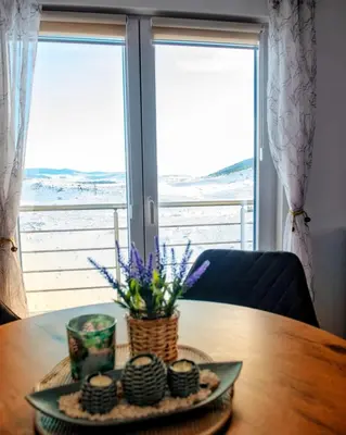 a table with a plate with flowers on it in front of a window at Vikendica Jadranka in Kupres