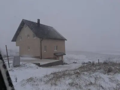a house in a field with snow on the ground at Vikendica Jadranka in Kupres