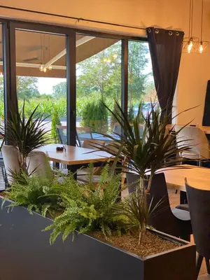 a restaurant with tables and chairs and plants at S Apart Rooms in Bosanska Gradiška