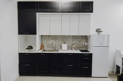 a kitchen with black and white cabinets and a refrigerator at S Apart Rooms in Bosanska Gradiška