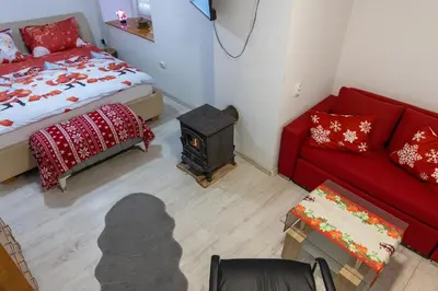 a living room with a red couch and a stove at Guest House Lejla in Travnik