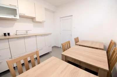 a kitchen with white cabinets and wooden tables and chairs at Apartmani Sebastijan in Banja Luka