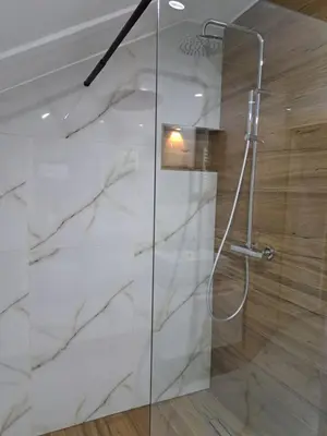 a bathroom with a shower with white marble at Apartman Mihaela in Laktaši