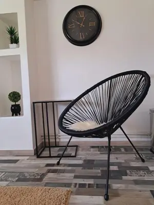 a black chair in a room with a clock on the wall at Apartman Mihaela in Laktaši