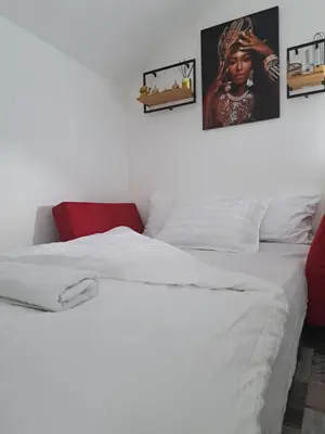 a bed with white sheets and pictures on the wall at Apartman Mihaela in Laktaši