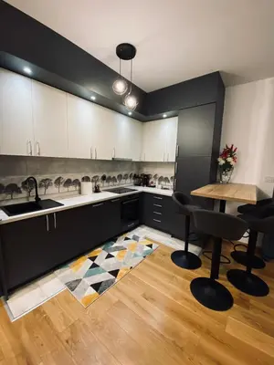 a kitchen with black cabinets and a table and chairs at Apartman Stojić in Banja Luka