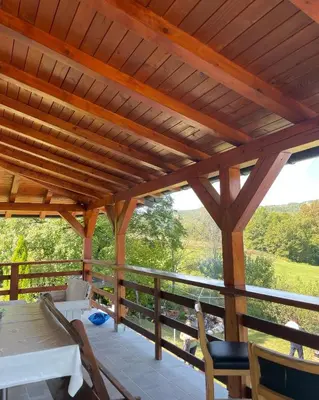 a wooden pergola with a table and chairs on a porch at Vikendica Krupa in Banja Luka