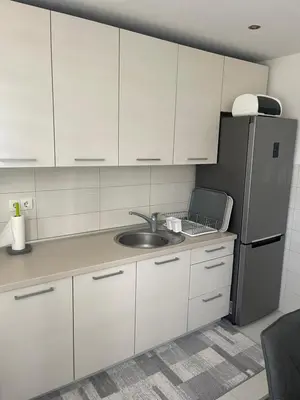 a kitchen with white cabinets and a sink and a refrigerator at Apartman IN in Banja Luka