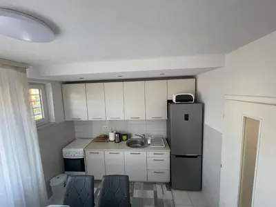 a small kitchen with white cabinets and a refrigerator at Apartman IN in Banja Luka