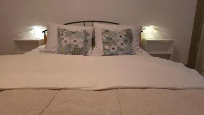 a white bed with pillows and two lamps on tables at Evergreen in Banja Luka