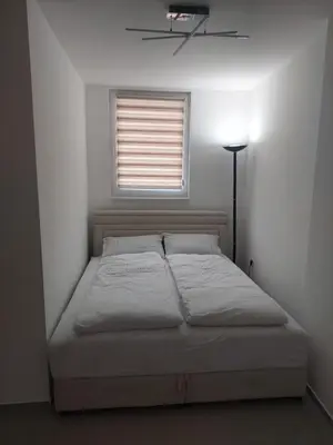 a bed in a white room with a window at Apartman Magus in Tuzla