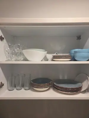 a shelf filled with plates and bowls and glasses at Apartman Magus in Tuzla