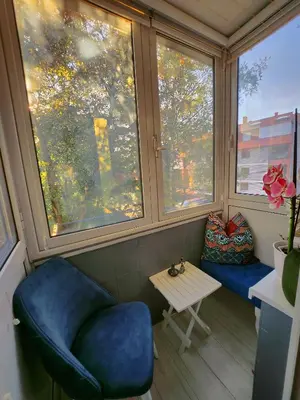 a room with a blue chair and a table and windows at Apartman TaMaRa in Doboj