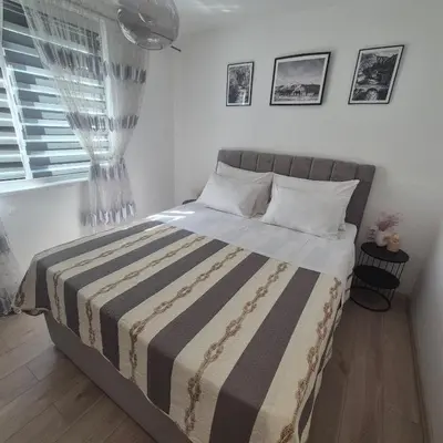 a bedroom with a bed with a striped blanket at Apartman Rita in Livno