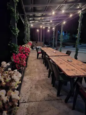 a long wooden table in a room with flowers at Vikendica Tuzla, Dolina mira in Tuzla