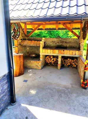 a wooden bench sitting under a building with a roof at Vikendica Tuzla, Dolina mira in Tuzla