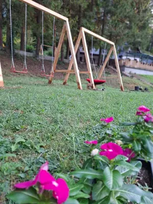 a group of swings in a yard with flowers at Vikendica Tuzla, Dolina mira in Tuzla