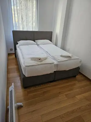 a bed in a bedroom with a wooden floor at APARTMAN CENTAR BULEVAR EX sa GARAZOM in Banja Luka