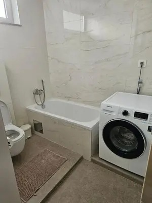 a bathroom with a washing machine and a toilet at APARTMAN CENTAR BULEVAR EX sa GARAZOM in Banja Luka