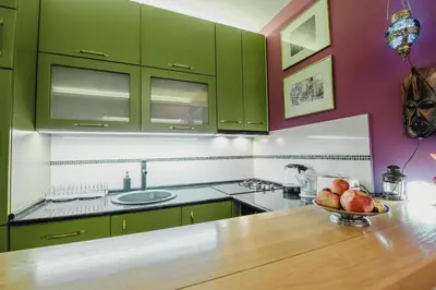 a kitchen with green cabinets and a bowl of fruit on a counter at Divan Apartman u Banjaluci in Banja Luka