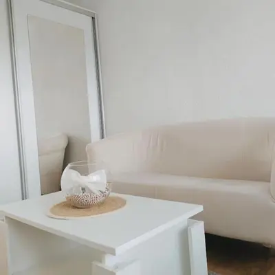 a white couch and a table with a bowl on it at White home apartment in Banja Luka
