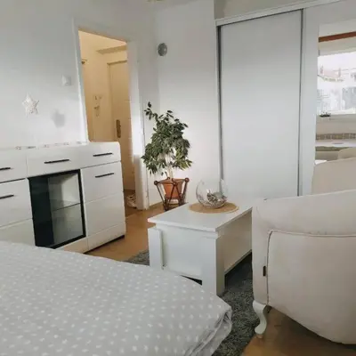 a white living room with a couch and a table at White home apartment in Banja Luka