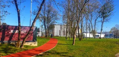 a red path in a park with trees and a building at Parkpoint in Banja Luka
