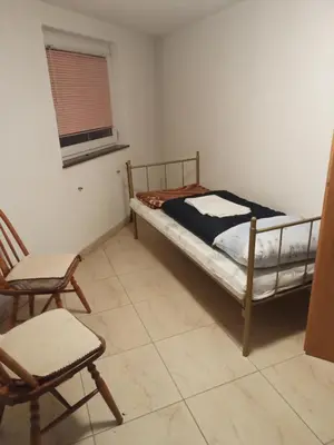 a bedroom with a bed and a chair and a window at Apartman SM IK 1 in Tomislavgrad