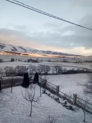 a field covered in snow with a fence and trees at Apartman SM IK 1 in Tomislavgrad
