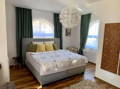 a bedroom with a bed with green curtains and a chandelier at Sokograd Loft in Šipovo