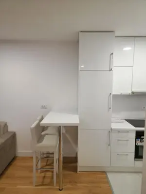 a kitchen with white cabinets and a table and chairs at Apartment 4th. Floor II in Banja Luka