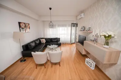 a living room with a black leather couch and white chairs at City Museum 2 Apartments Banja Luka in Banja Luka