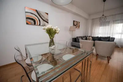 a living room with a glass table with a vase of flowers at City Museum 2 Apartments Banja Luka in Banja Luka