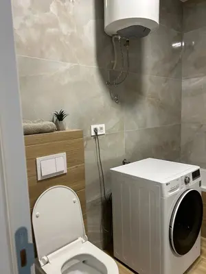 a bathroom with a toilet and a washing machine at D&ALux apartman in Banja Luka