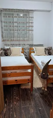 a bedroom with two beds and a bird standing between them at Apartman Maximus in Kupres