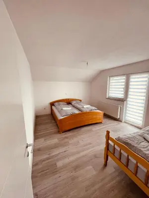 two beds in a room with two windows at Kuca za odmor Nedo in Kupres