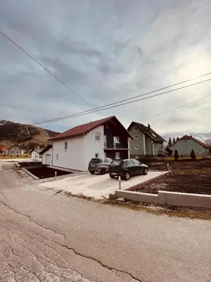 a house with two cars parked in a parking lot at Kuca za odmor Nedo in Kupres
