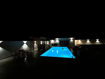 a swimming pool in the dark with chairs and a table at Romantic Lodge in Banja Luka