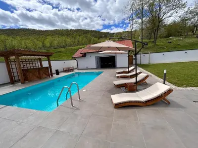 a swimming pool with two lounge chairs and an umbrella at Romantic Lodge in Banja Luka
