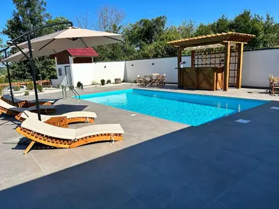 a swimming pool with lounge chairs and an umbrella at Romantic Lodge in Banja Luka