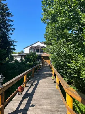 a wooden walkway leading to a house with trees at Haus Palazzo in Bosanska Krupa