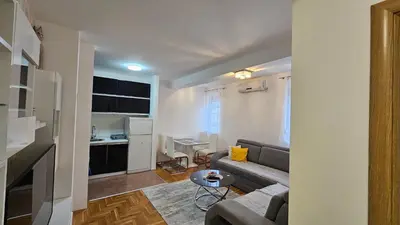 a living room with a couch and a small kitchen at Apartman Dolores in Banja Luka