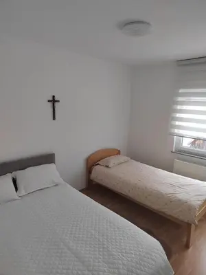 a bedroom with two beds and a cross on the wall at Apartman Lara in Kupres