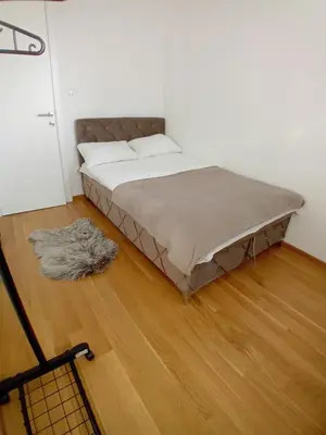 a bed in a room with a wooden floor at Stan na dan Apartman ADA Banjaluka in Banja Luka