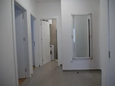 a white hallway with a mirror and a bathroom at Stan na dan Apartman ADA Banjaluka in Banja Luka